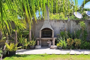 An outdoor area with a concrete structure, possibly a barbecue or grill, surrounded by various potted plants and greenery.