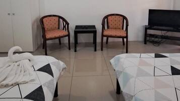 A hotel room with two beds, a TV, a wardrobe, and two chairs.