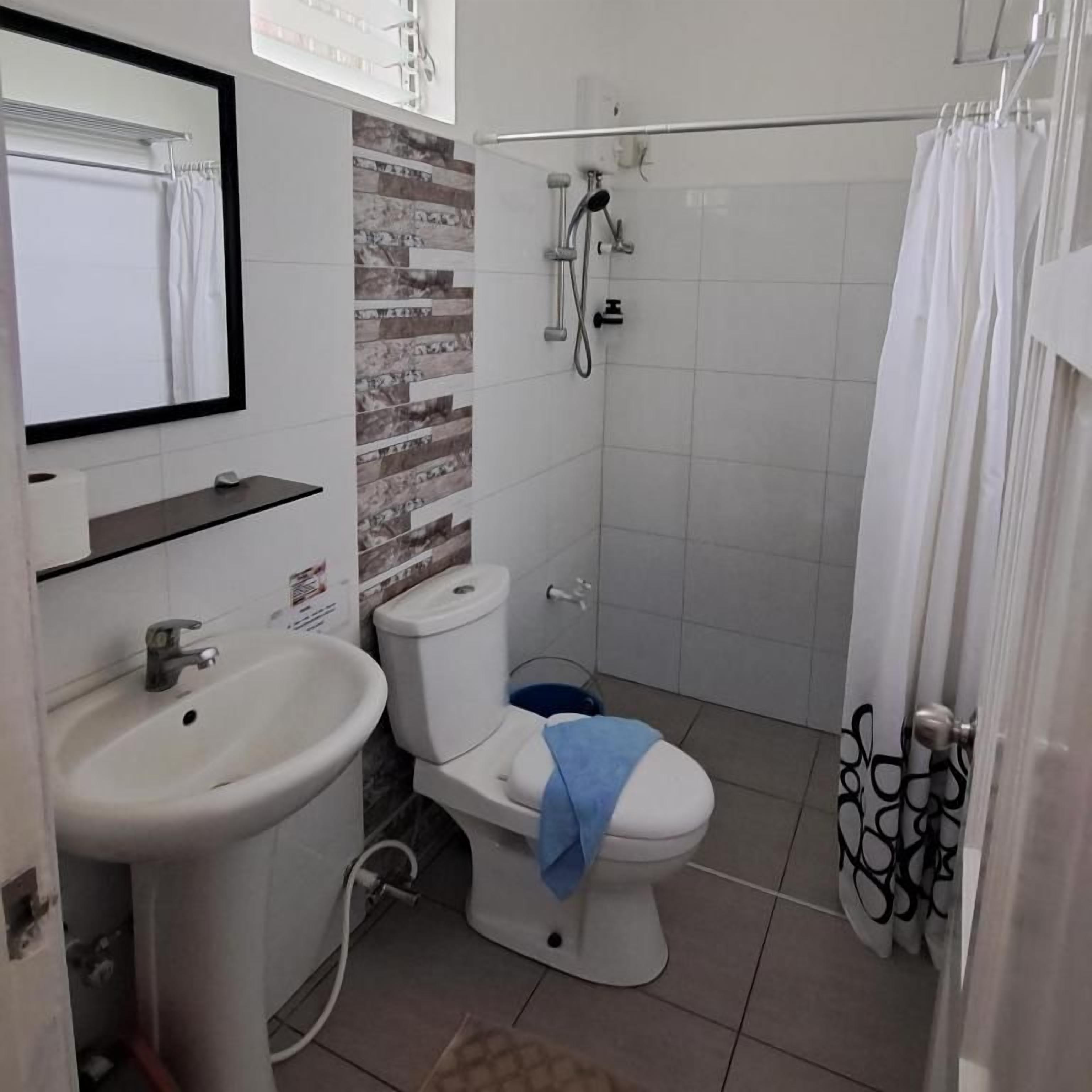 Een badkamer met toilet, wastafel, douche en spiegel.
