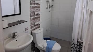 Een badkamer met toilet, wastafel, douche en spiegel.