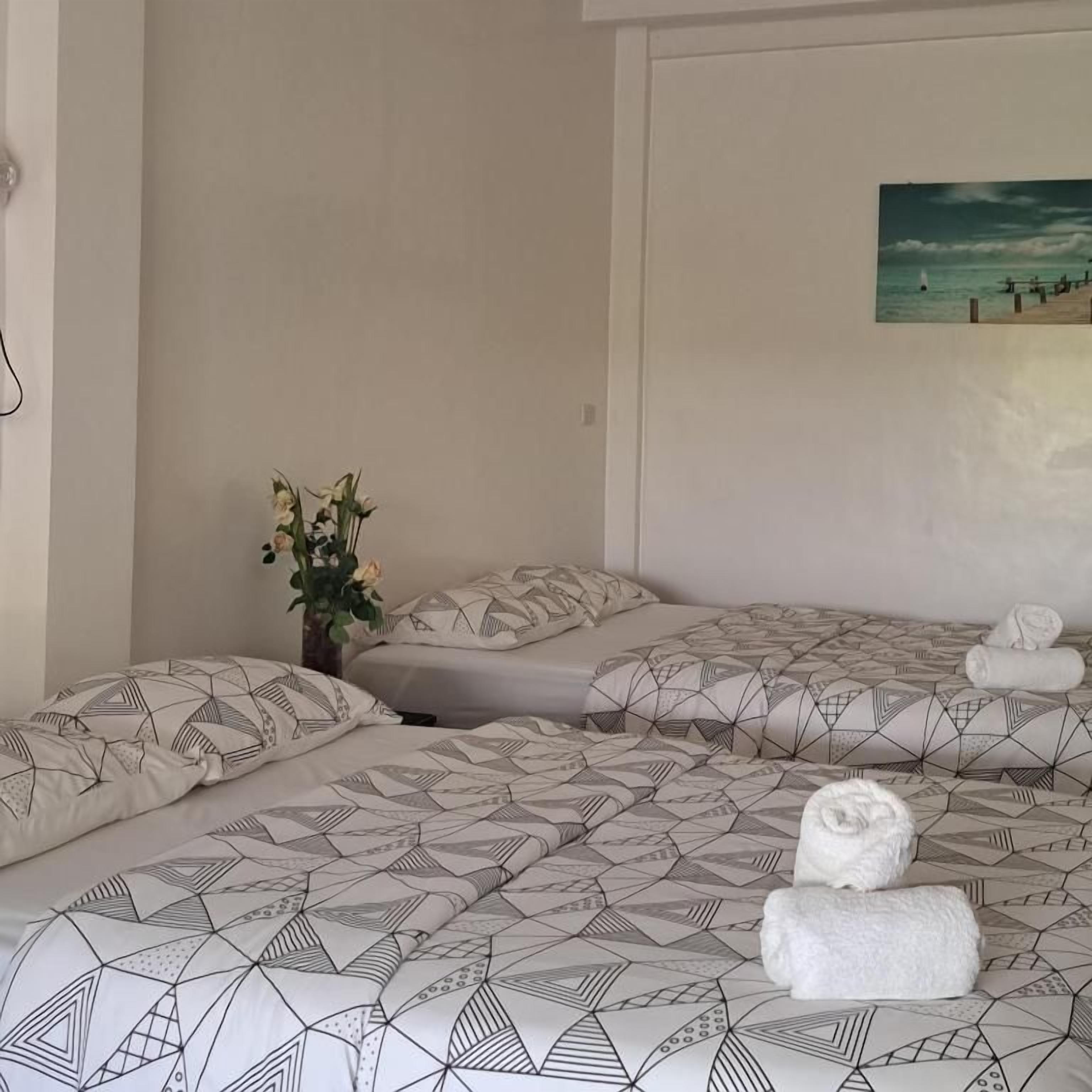 Ein Hotelzimmer mit zwei Betten, einem Strandbild und einer Blumenvase.
