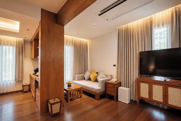 A modern living room with a sofa, TV, and wooden furniture. - River View Village  (Chiang Mai)