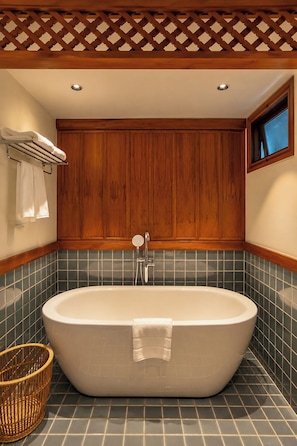 A bathroom with a freestanding bathtub, wooden paneling, and a tiled floor. - River View Village  (Chiang Mai)