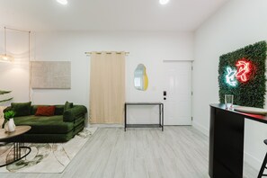 Ein modernes Wohnzimmer mit einem grünen Sofa, einem kleinen Tisch und einem dekorativen Spiegel.