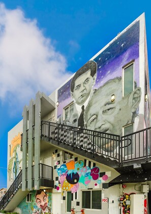 Ein Gebäude mit Wandmalerei, die zwei Gesichter, eine Treppe und ein farbenfrohes Graffiti-Design zeigt.