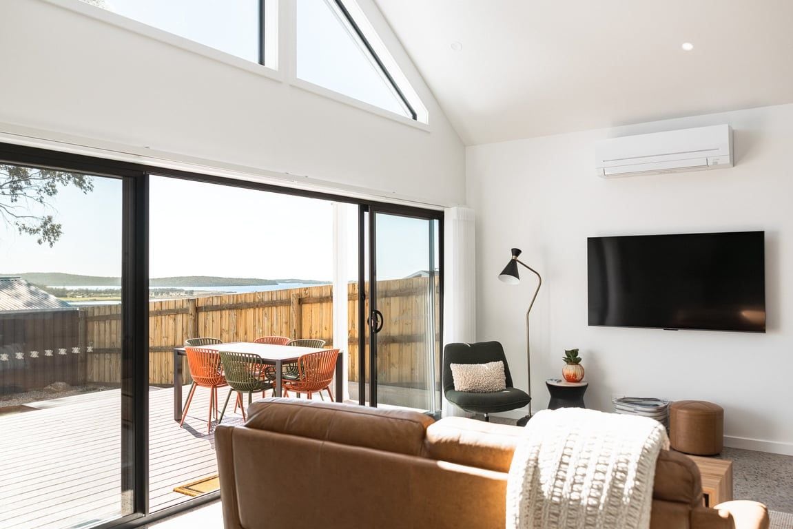 A modern living room with a large sliding glass door leading to an outdoor patio area.
