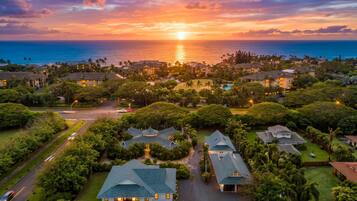 A residential area with houses, a swimming pool, and a sunset view.