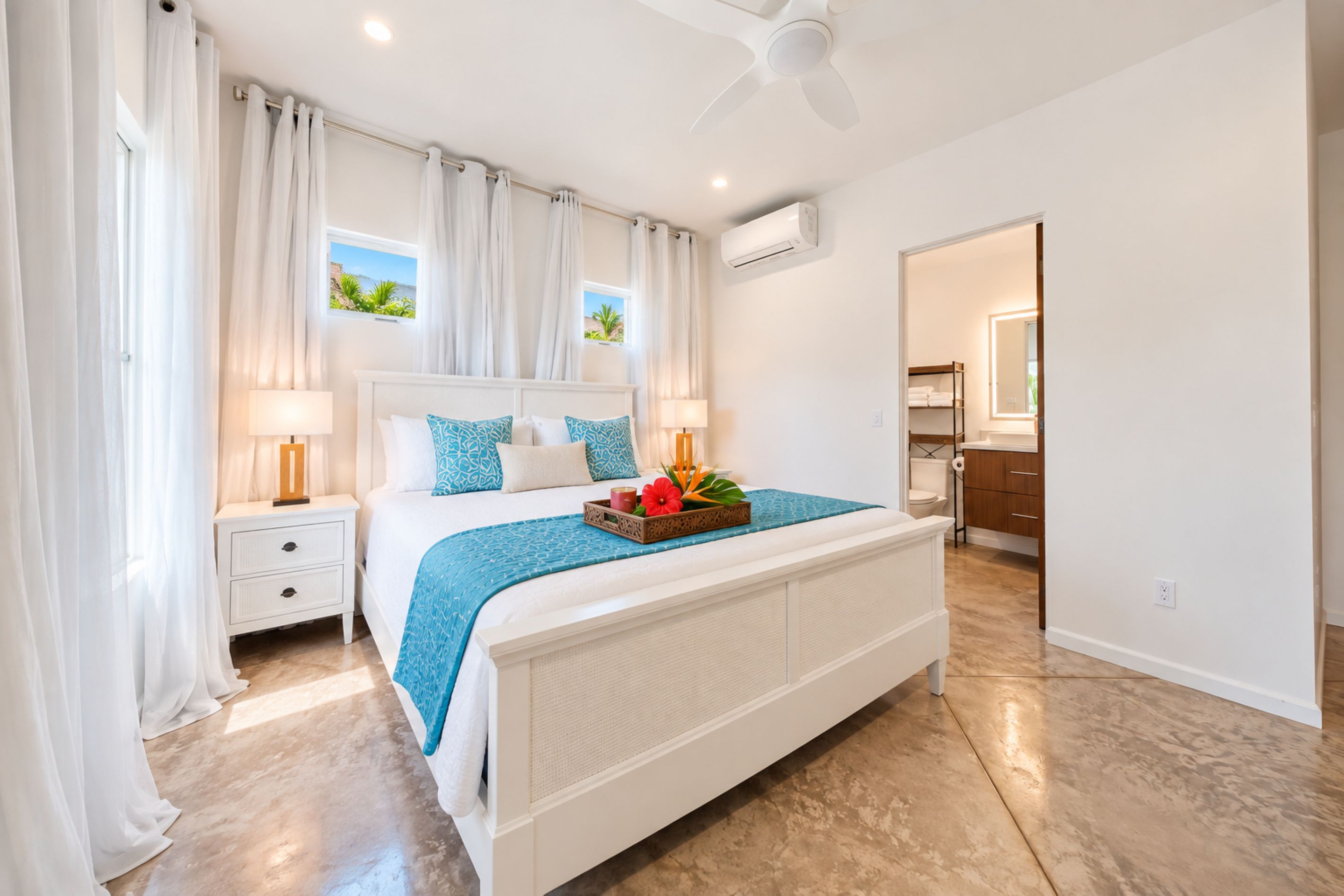 A bedroom with a bed, nightstands, a ceiling fan, and a view of the outdoors.