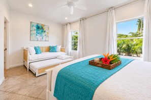 A bedroom with a bed, a sofa, a ceiling fan, a window with curtains, and a painting on the wall. - BRAND NEW Poipu Estate - Sleeps 8-16 - Full AC - 4 Ensuites - Poipu Beach Club (Koloa)
