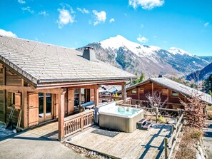 A wooden cabin with a hot tub and deck, surrounded by mountains. - Chalet Cerf, Sleeps 10, Hot Tub, Ascension Immobilier (LA COTE D ARBROZ)