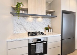 Una cocina moderna con protector de salpicadero de mármol, electrodomésticos de acero inoxidable y horno empotrado.