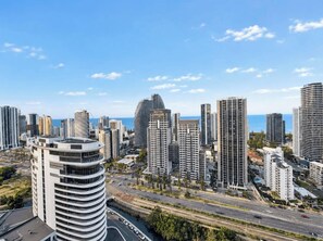 A cityscape with high-rise buildings, a curved structure, and a clear sky. - Luxe 2BR @ The Star | Ocean+River Views, Pool, Gym (Broadbeach)