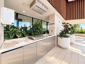A modern kitchen with a built-in sink, stainless steel cabinets, and potted plants. - Luxe 2BR @ The Star | Ocean+River Views, Pool, Gym (Broadbeach)