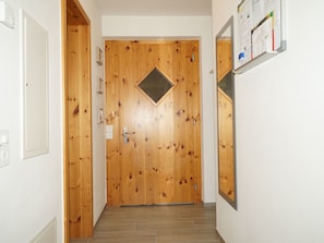 En dörr av trä med en diamantformad ventil, en ljusströmbrytare och en spegel som är monterad på väggen.