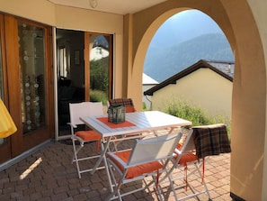 Eine Außenpatio mit Tisch und Stühlen, eine Schiebetür aus Glas und Blick auf ein Gebirge.