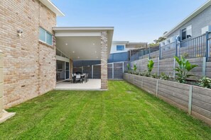 Ein modernes Haus mit überdachter Terrasse, Ziegelaußenwand und gepflegtem Rasen.