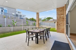 Eine Terrasse im Freien mit Esstisch und Stühlen, mit Blick auf eine Wohngegend.