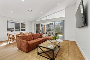 Una sala moderna con un sofá seccional, una mesa de centro y un comedor con sillas y una mesa.