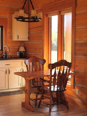 Un interno in legno con un tavolo da pranzo e sedie, un lampadario e una finestra vista.