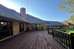 Un patio in legno con un edificio in mattoni, dotato di camino e ampie finestre.