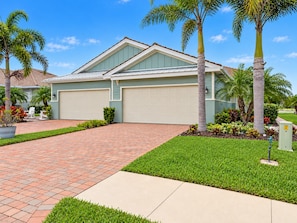 A residential house with a garage, a paved driveway, and a well-maintained lawn. - Lakeview Villa 2-bedroom 2 Bath plus den - pool! (Naples)