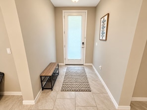 A hallway with a bench, a rug, and a door with blinds. - Lakeview Villa 2-bedroom 2 Bath plus den - pool! (Naples)