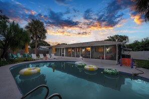Ein Pool mit Liegestühlen und einer überdachten Terrasse.