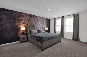 Een slaapkamer met een groot bed, twee nachtkastjes, een muurschildering en een raam met gordijnen.
