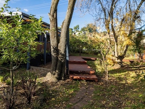 A garden with a wooden deck, trees, and a pathway.