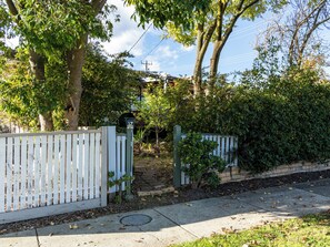A gated residential property with a mailbox, a concrete pathway, and a grassy area.