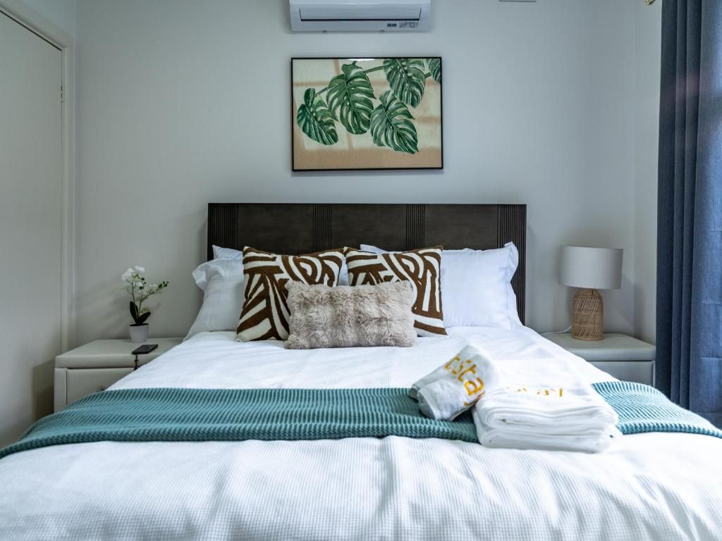 A neatly made bed with a striped blanket, pillows, and a folded towel.