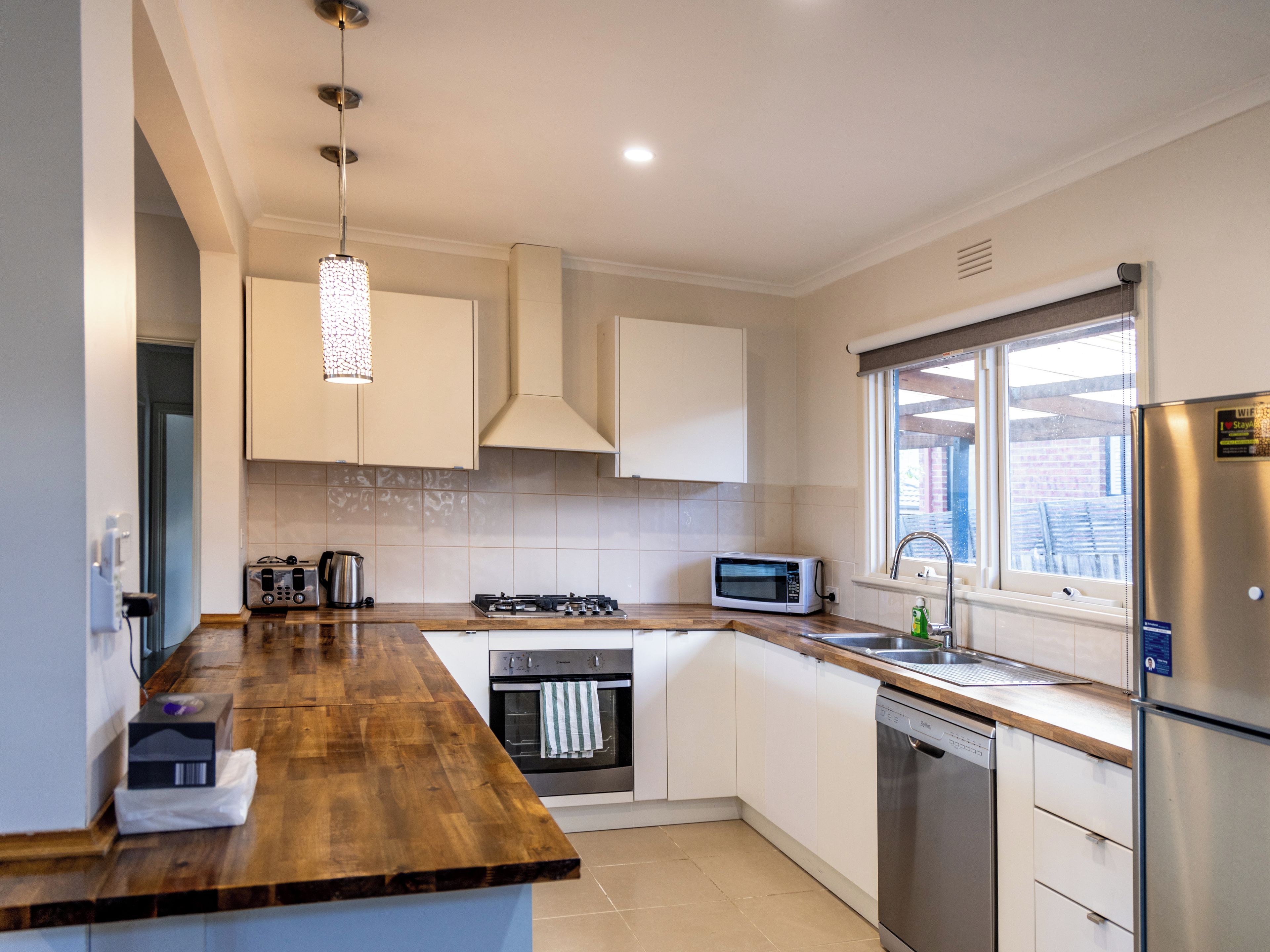 A modern kitchen with a wooden countertop, stainless steel appliances, and a window providing natural light.