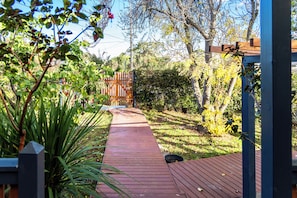 A wooden pathway leading through a garden with various plants and trees.