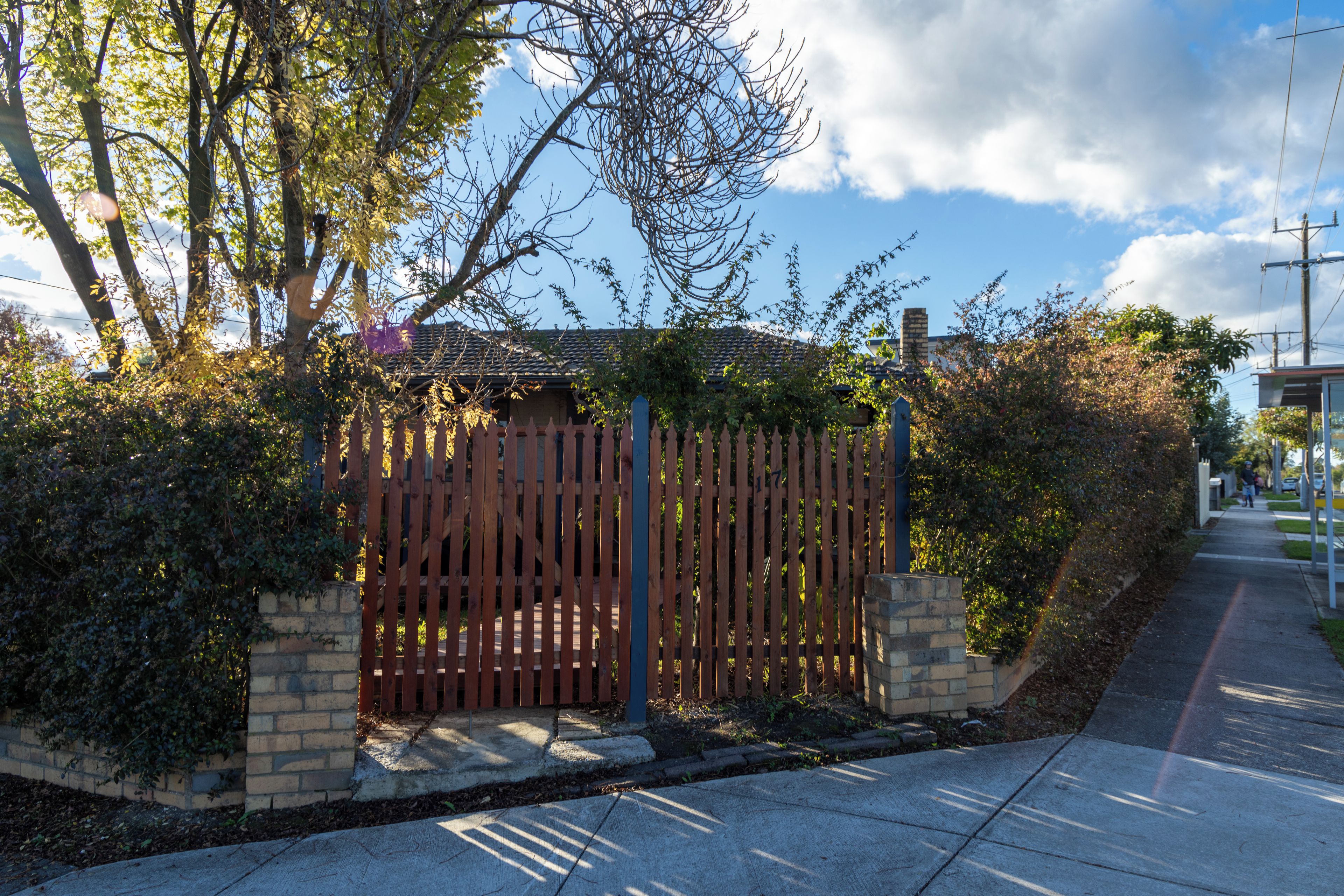 A gated property with a brick wall, wooden fence, and a clear sky.