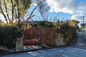 A gated property with a brick wall, wooden fence, and a clear sky.