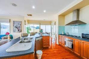 A modern kitchen with a central island, wooden cabinets, and a stainless steel range hood.