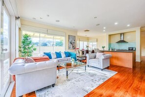 A spacious living area with a sofa, coffee table, and a kitchen in the background.