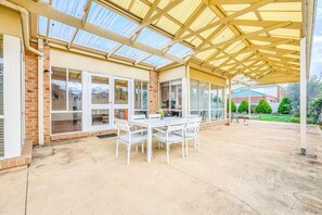 A covered patio area with a table and chairs, a brick wall, and a glass door.