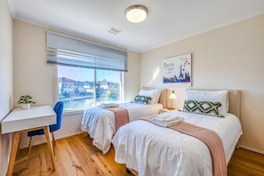 Habitación de hotel con dos camas, un escritorio y ventana con vista a la ciudad.