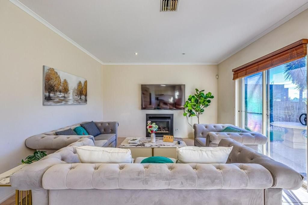 A living room with a sofa set, a flat-screen TV, a fireplace, and a large window with a view.