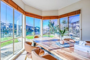 A modern dining area with a large table, multiple chairs, and a view of the city through large windows.