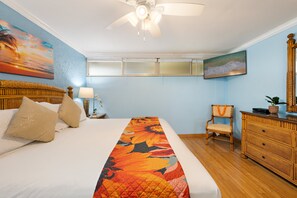 A hotel room with a bed, a chair, a dresser, a ceiling fan, and a painting on the wall. - 2nd Floor Oceanfront 1BD with Panoramic Island Views -Kahana Reef 217 (Lahaina)