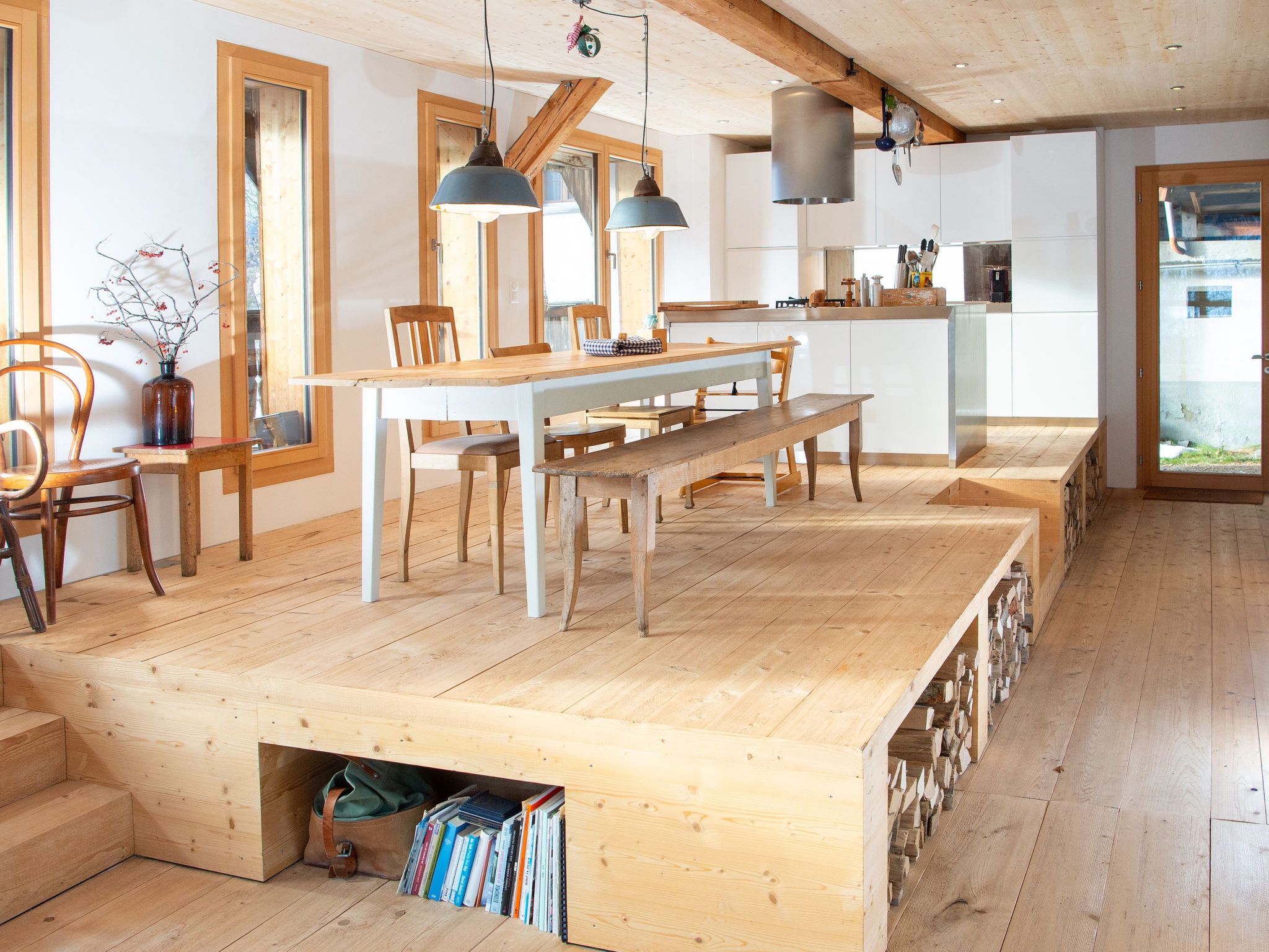 Cucina spaziosa con pavimento in legno, isola centrale e luci a sospensione.