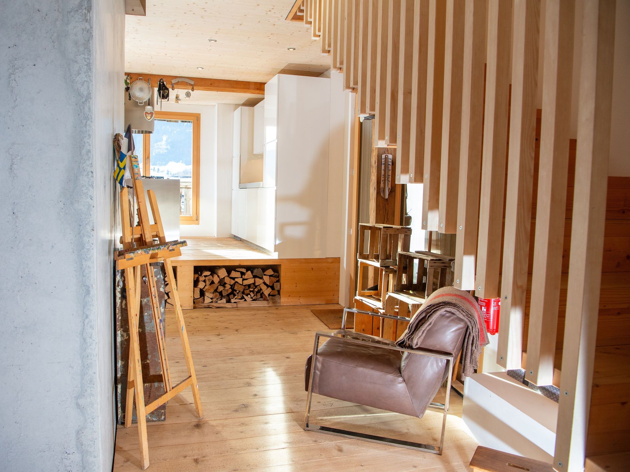 Una habitación con piso de madera, un sillón de cuero marrón, una estantería de madera y una chimenea.