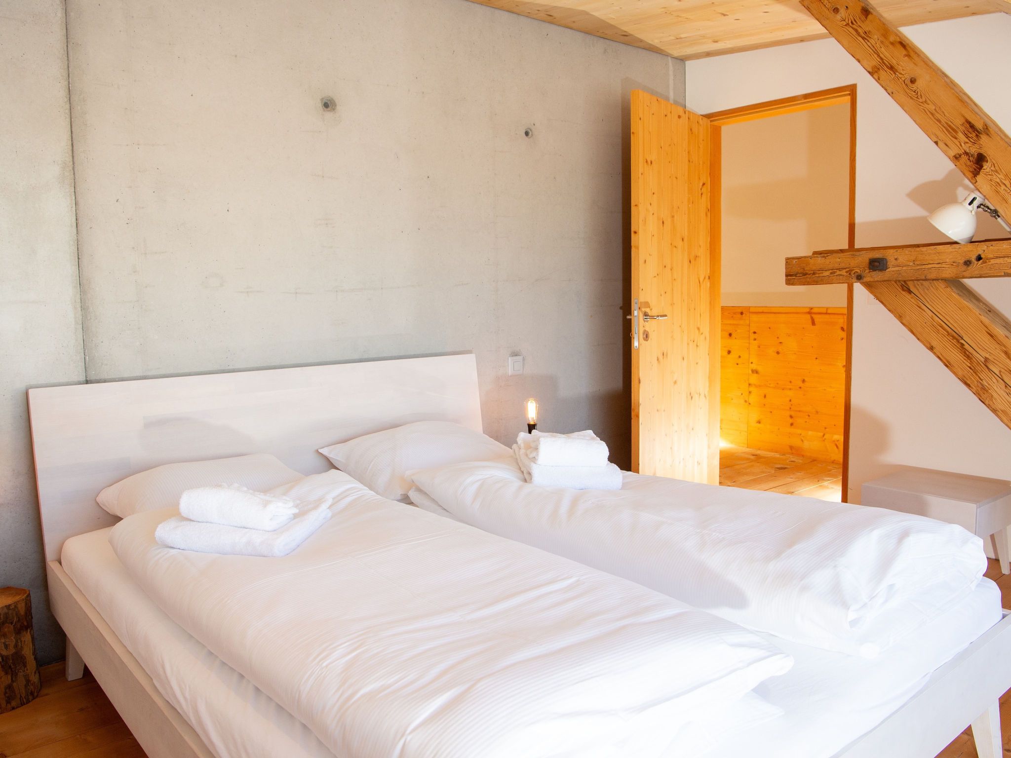 Une chambre à coucher avec un grand lit, un plafond en bois et une porte donnant sur une autre pièce.
