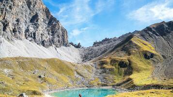 Eine Berglandschaft mit einem See und einer Person beim Laufen.