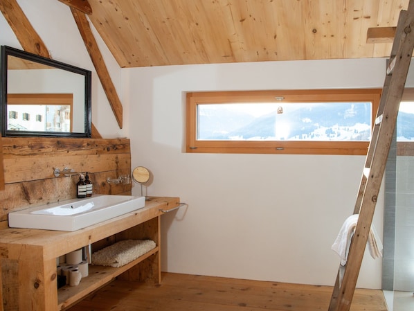 A wooden bathroom with a large window, a mirror, and a sink.