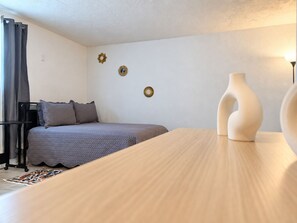Een slaapkamer met een bed, nachtkastje, lamp en decoratie aan de muur.