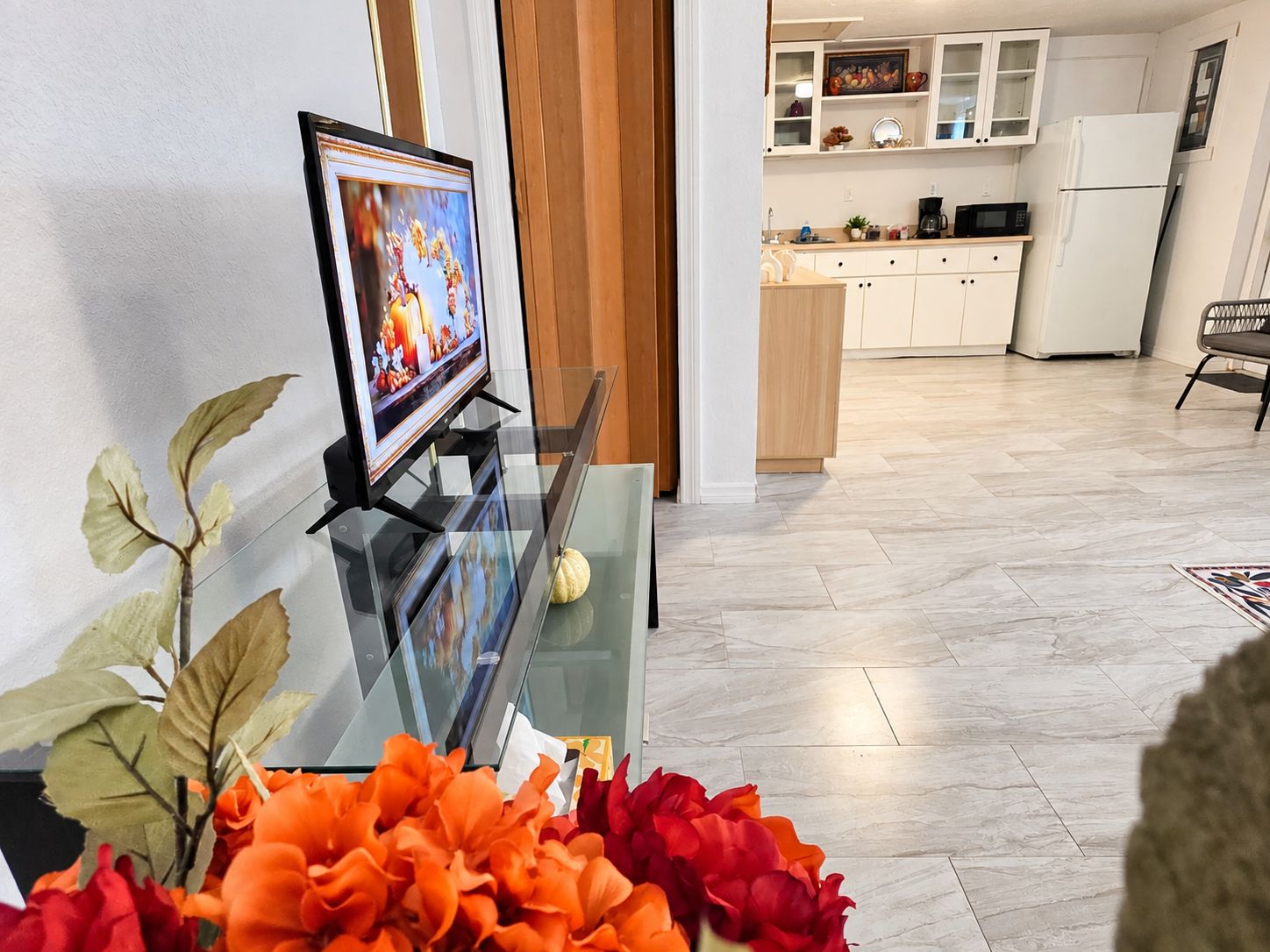 Una sala de estar con una mesa de centro de vidrio, un televisor y plantas decorativas.