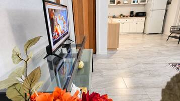 Una sala de estar con una mesa de centro de vidrio, un televisor y plantas decorativas.